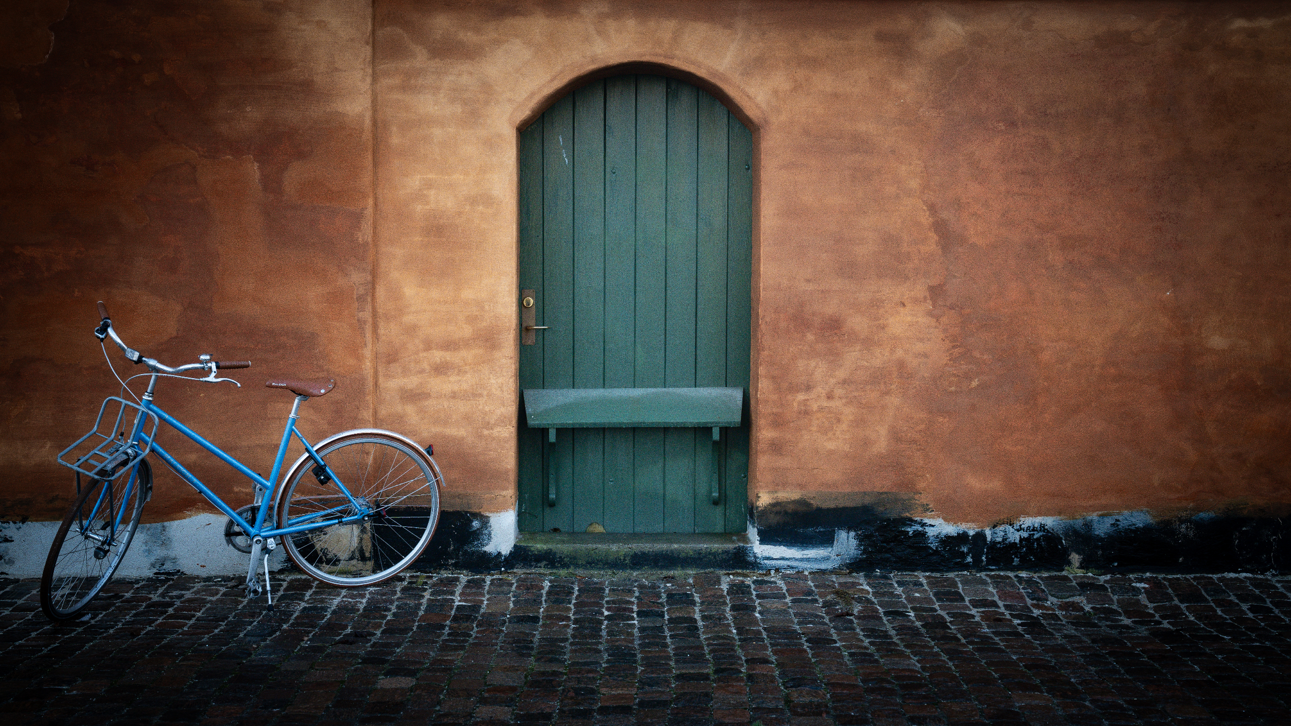Old wooden door set in to a stone wall with a bike standing outside